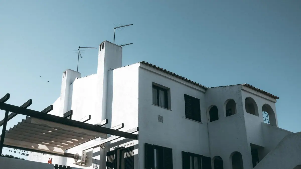 White stucco home with chimneys under a clear sky