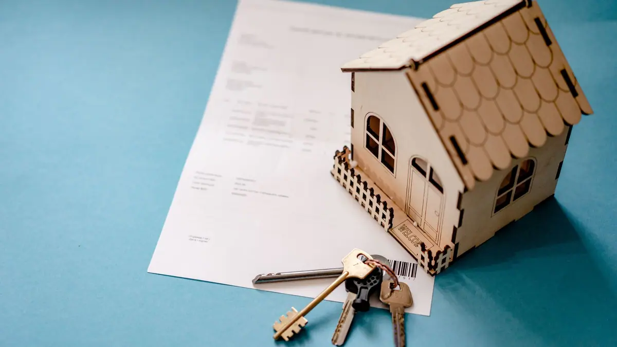 Small wooden house model, house keys, and permit paperwork on a table