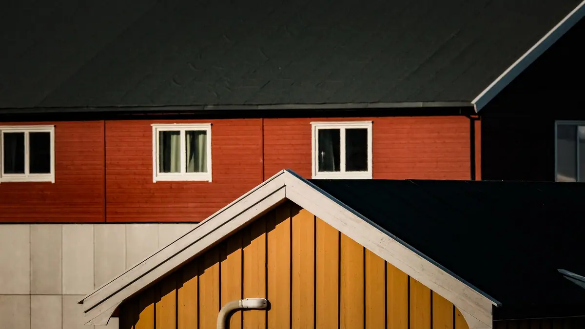 Red-orange wall and yellow gabled entry with a downspout