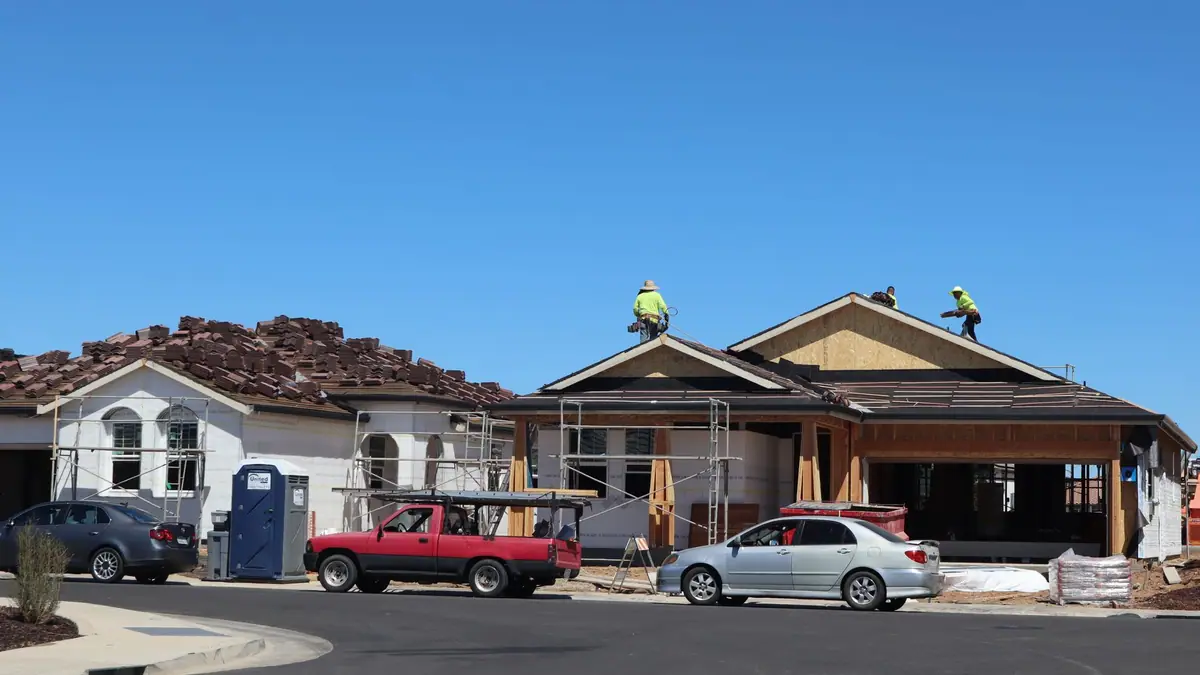 Contractors working on the roof of a home under construction in a subdivision