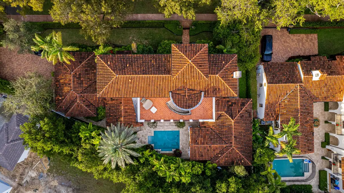 Aerial view of a large estate with a tile roof and swimming pool