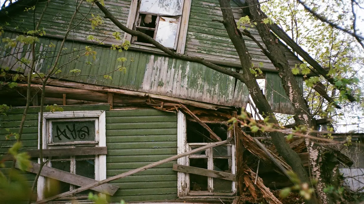 Storm-damaged wooden house with fallen branches