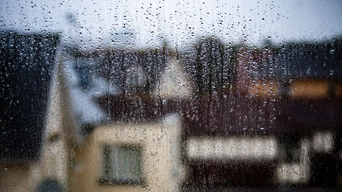 Raindrops on a window with a house in the background