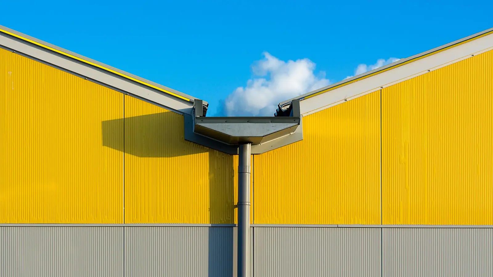 Yellow commercial building with a gutter and downspout under a blue sky