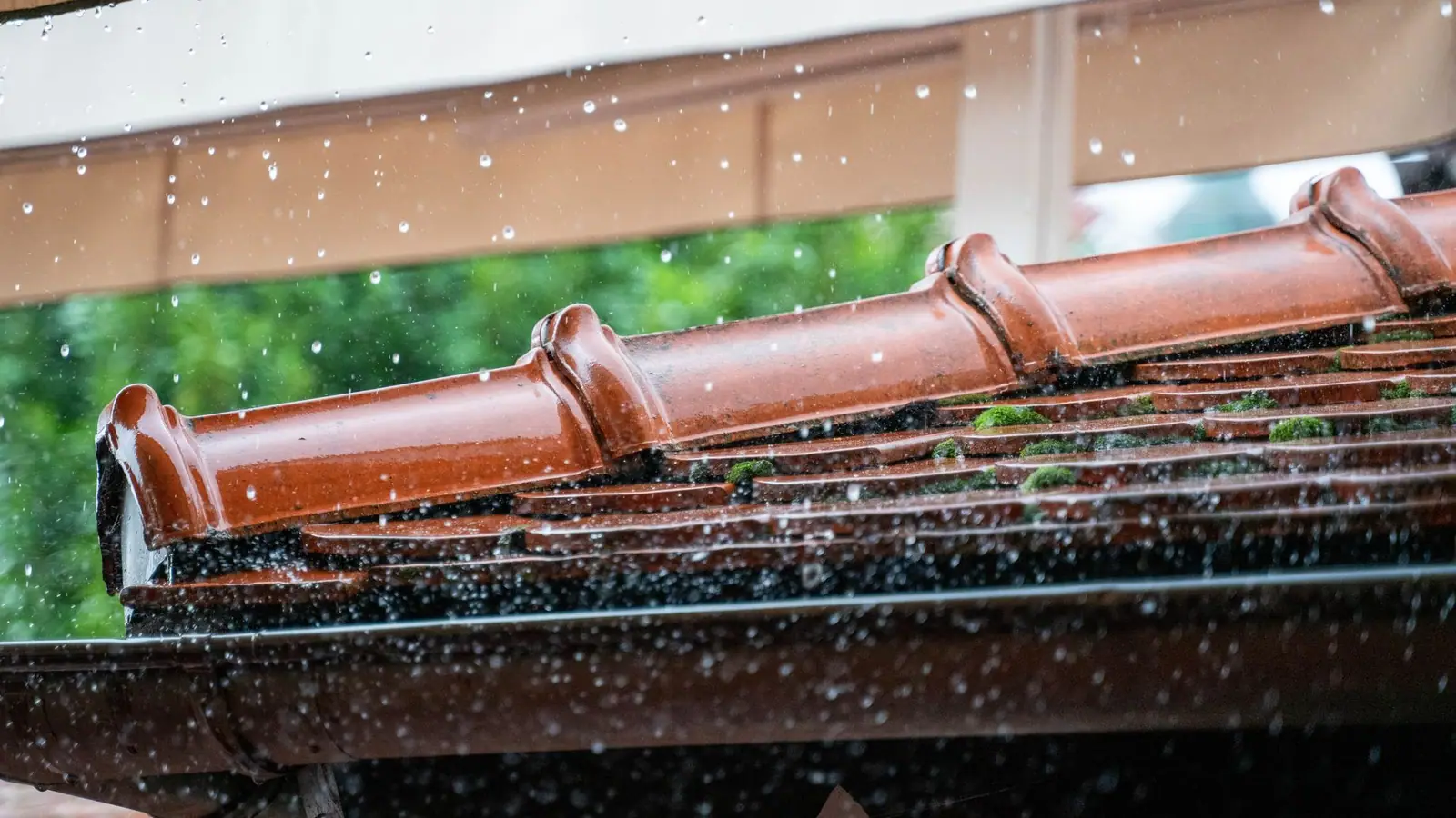 Rain running off the edge of a clay tile roof into a gutter