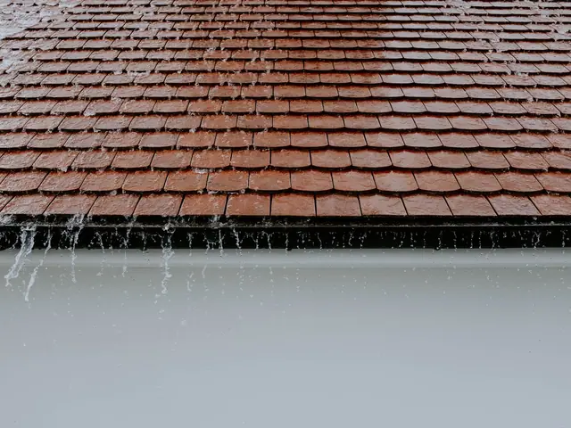 Rain running off the edge of a clay tile roof into a gutter