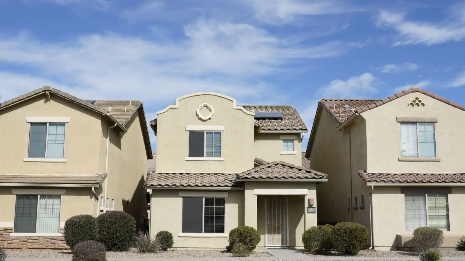 Two-story stucco homes with tile roofs and gutters in a Florida suburb